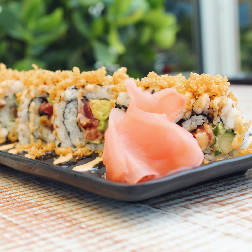 Sushi rolls with crispy topping and pickled ginger on a black plate at The Bite Eatery.