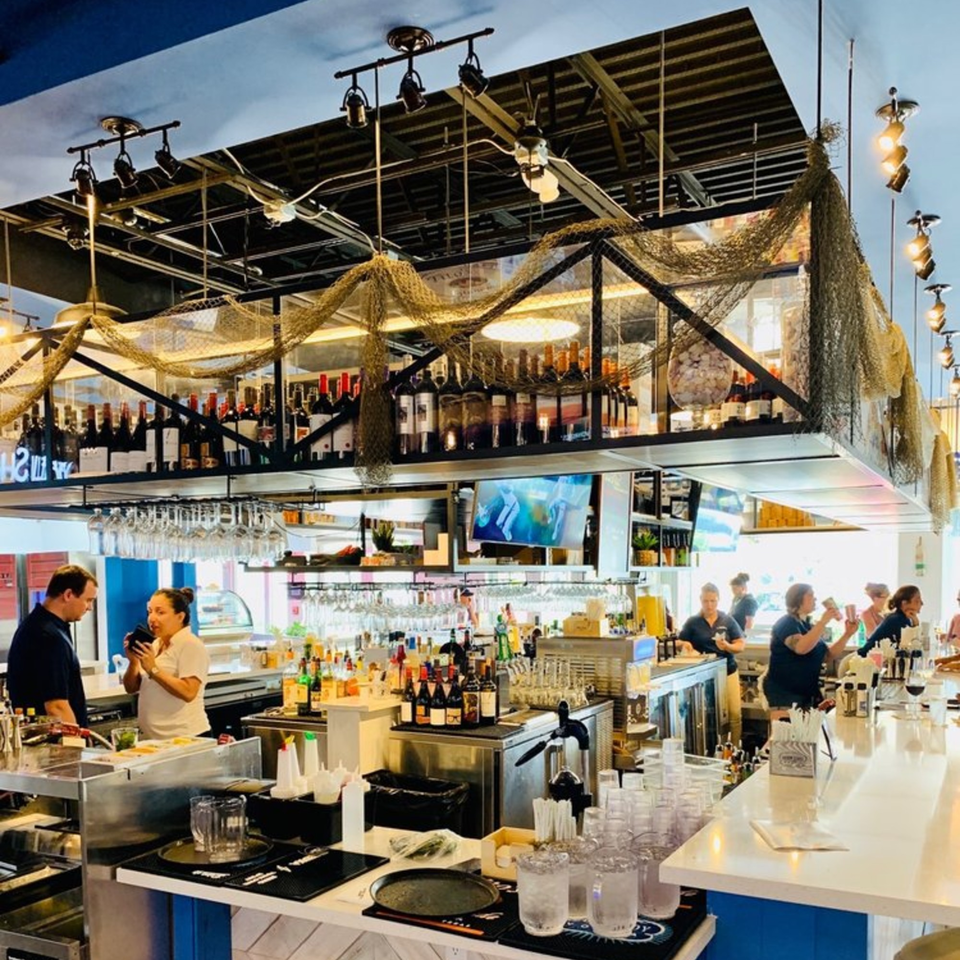 The Bite Eatery's bar area with bottles of alcohol, fishing net decor, and staff working.